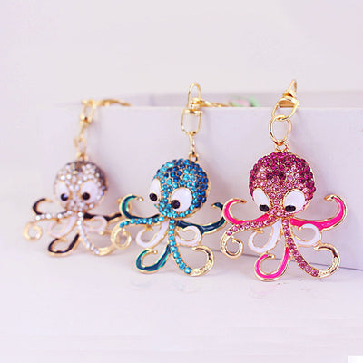 Three gold-tone octopus keychains in gray, blue, and pink rhinestone designs.