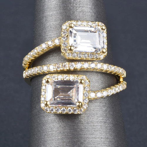 Yellow gold dual emerald halo bypass ring on gray finger cone