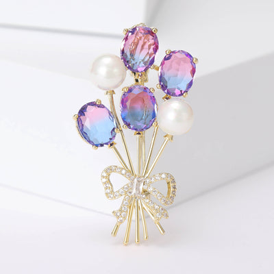 Front view of balloon-bouquet brooch with gradient crystals and white pearls against a white background.
