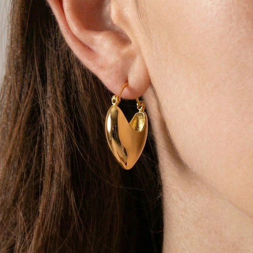 Gold heart shield hoop earring worn on ear with dark hair