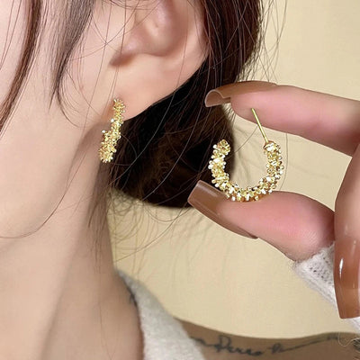 Gold irregular crystal C-hoop stud earring held near ear