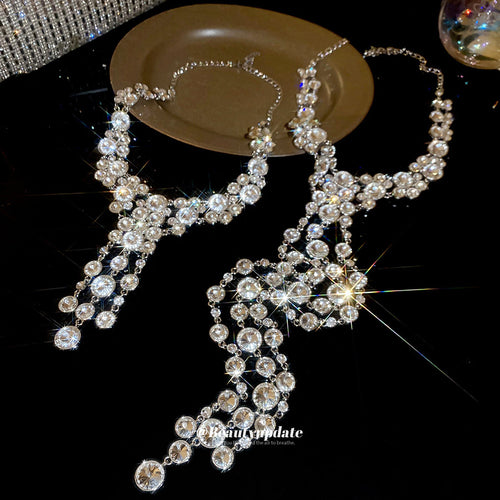 silver tone crystal y drop statement necklace with metal tone details shown in an on-ear styling view