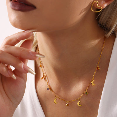 Close-up model wearing gold crescent moon rhinestone charm necklace