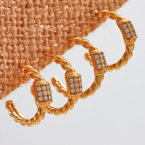 Three gold twisted rope C hoops with pave cubes on woven fabric