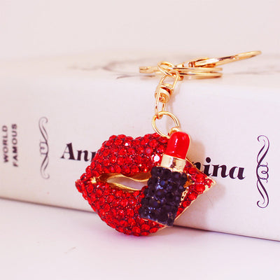 Close-up of red rhinestone lips and a lipstick charm attached to a gold-tone keyring.