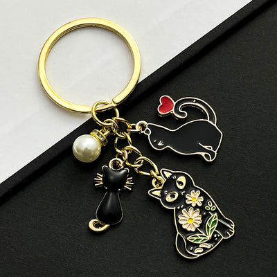 Front product photo of black cat heart and faux pearl enamel charm keychain showing the pictured design arrangement