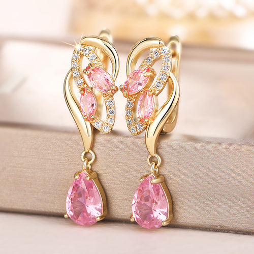 Gold pink twist teardrop earrings showing post backs on beige fabric