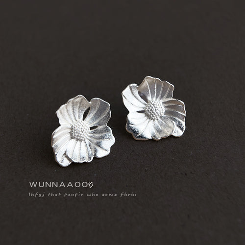 Silver matte flower studs on dark gray fabric surface