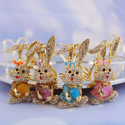 Four gold-tone rabbit keychains with pink, blue, purple, and light brown rhinestone details.