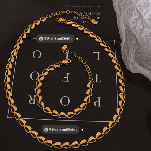Gold heart link necklace and bracelet flat on black board with size callouts