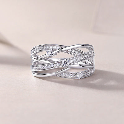 Silver multi-band crossover CZ ring standing on pale surface