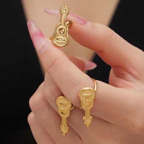 Close-up gold guitar rings worn on fingers