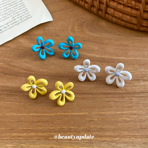 Styled view of open enamel flower stud earrings in yellow white and blue