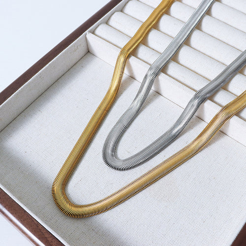 Gold and steel flat herringbone snake chains in cream jewelry tray