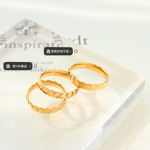 Three gold scalloped disc rings stacked on clear acrylic block