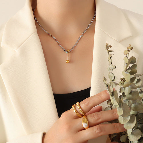 Model in cream blazer wearing steel chain gold U-bar necklace