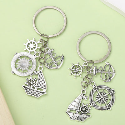 Two silver-tone keychains displayed with sailboat, anchor, ship wheel and compass charms.