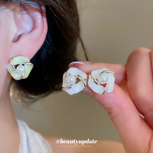 Styled view of sculpted flower stud earrings with pale inlays in two colors