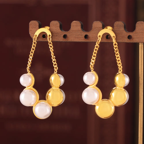 Gold pearl and metal bead drop pair hanging on wooden stand
