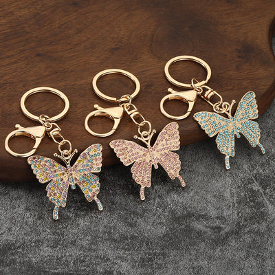 Three gold-tone butterfly keychains in multicolor, pink, and blue rhinestone styles.