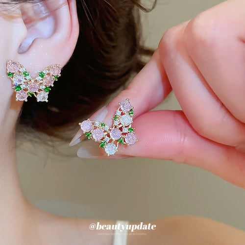 Butterfly silhouettes filled with pink, green, and clear crystals displayed in a close product arrangement.