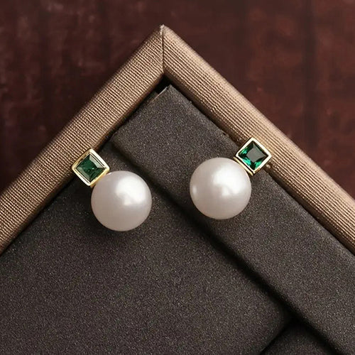Gold green stone pearl studs resting on black and tan display pad