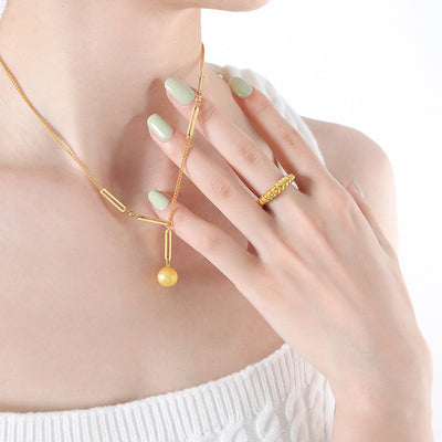 Model wearing gold Y necklace with frosted ball and bar links