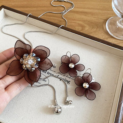 Brown mesh flower necklace and earrings flat lay in cream tray