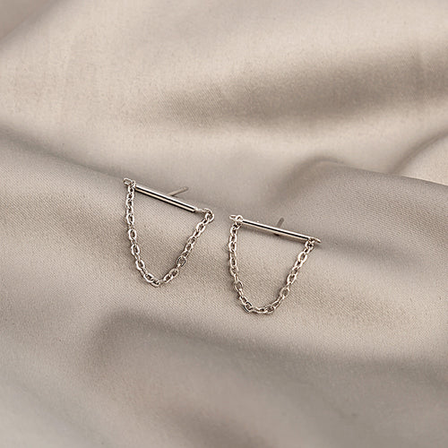 Silver bar stud earrings with dangling chain loops on beige fabric