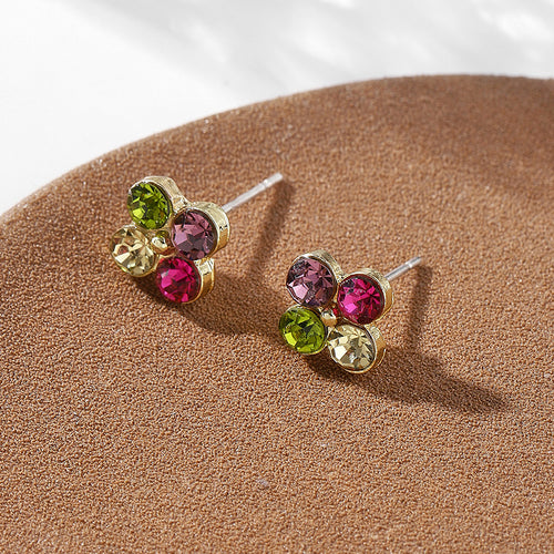 Multicolor crystal flower stud earrings angled on brown cork disc