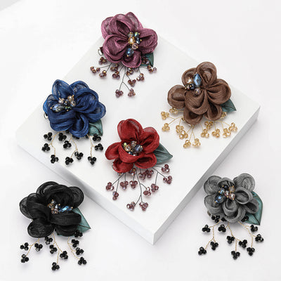 Purple Flower, Brown Flower, Black Flower, Gray Flower, Blue Flower, Red Flower brooch styles arranged on a light displa