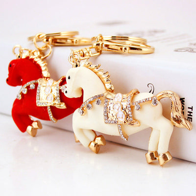 White and red rearing horse keychains displayed together with gold-tone rings.