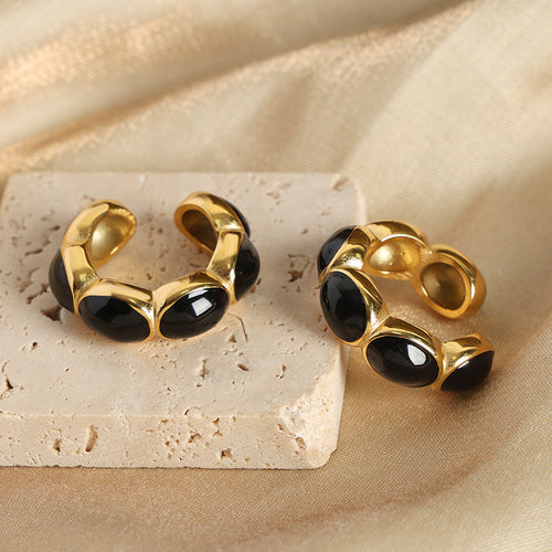 Pair of black enamel gold open hoops on stone surface