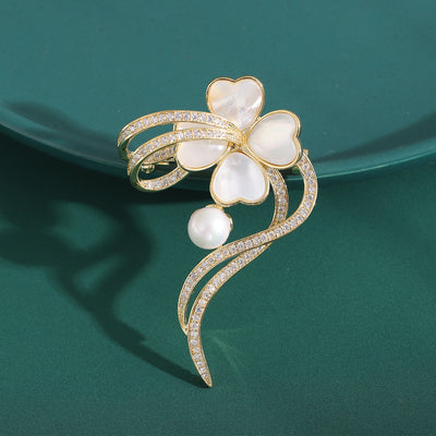Front view of shell-effect heart-petal flower brooch with pearl and curves against a white background.