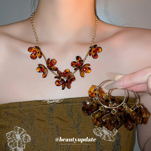 Tortoiseshell flower necklace worn with petal hoop earrings held