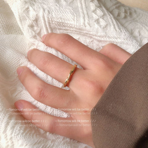 Twisted gold open ring worn on middle finger close-up