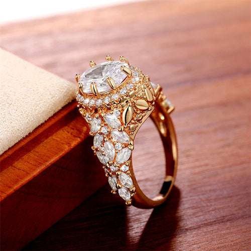 Gold tone oval cluster ring with clear stones, product displayed in a styled close-up