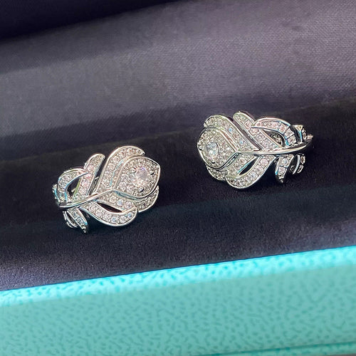 Silver rose petal pave huggies resting on dark velvet with teal rim