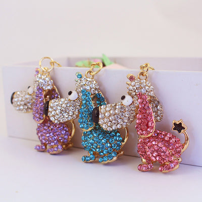 Three rhinestone-covered long-nose dog charms in purple, blue, and pink stand side by side.