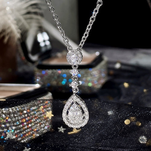 Silver teardrop pendant necklace hanging over dark glittery box