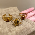 Three Gold Tone Brown Oval Round And Sunburst Stone Ring Designs view 2