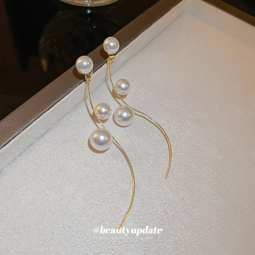 Styled close-up of curved wire pearl earrings