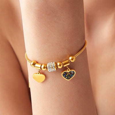 Gold heart charm snake bracelet worn on wrist with dual hearts