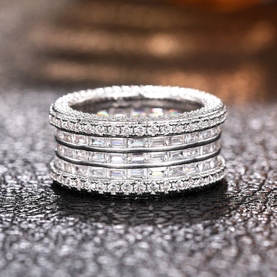 Wide multi-row baguette and pave crystal band ring on dark textured surface