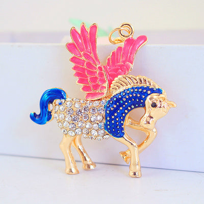 Front view of a gold-tone winged horse charm with pink wings, blue details, and clear rhinestones.