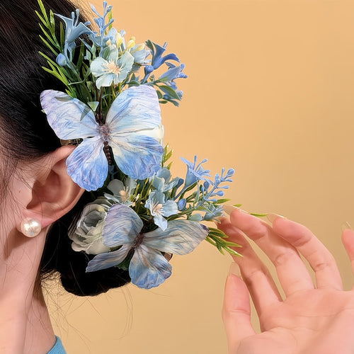 Blue butterfly floral spray clip worn at side of bun with hand adjusting