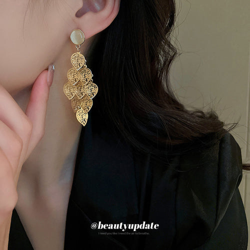 Styled close-up of gold tone leaf cluster earrings