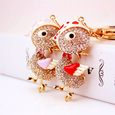 Red and purple rhinestone chicken keychains posed together.