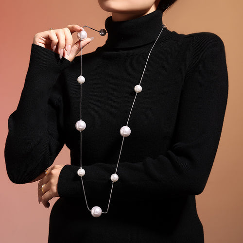 Silver long shell pearl station necklace on black turtleneck