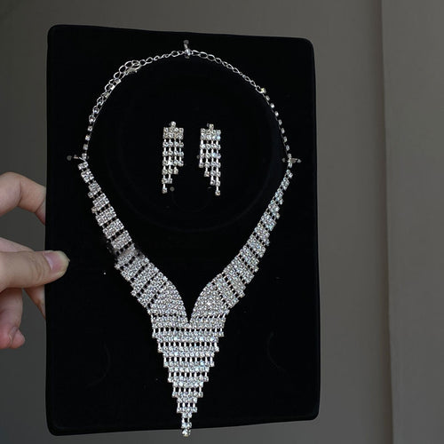 Silver V rhinestone tassel necklace and stud earrings on black bust